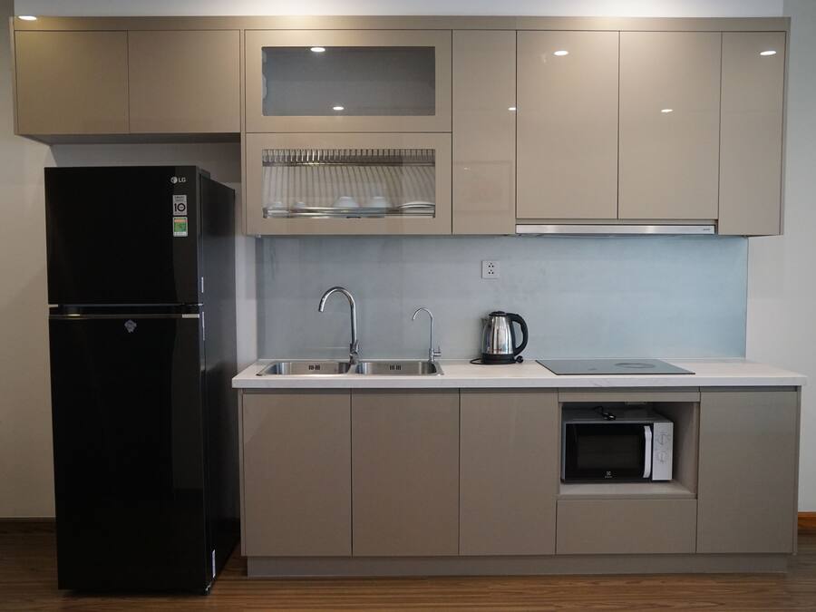 A modern kitchen with a black refrigerator, stainless steel sink, and a built-in microwave.