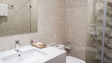 A modern bathroom with a large sink, mirror, and shower.