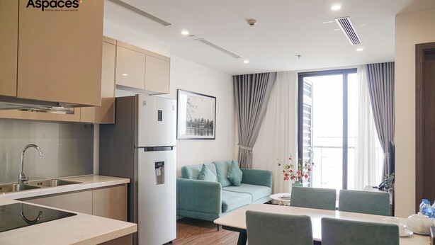 Une cuisine moderne équipée d’appareils électroménagers en acier inoxydable, un coin repas avec une table et des chaises, et un espace de vie avec un canapé.