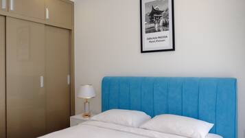 A bedroom with a large bed, a nightstand with a lamp, and a wardrobe.
