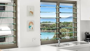 Eine moderne Küche mit einem großen Fenster, das einen malerischen Blick auf einen See und Berge bietet.