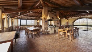 Un'ampia sala da pranzo con tavoli e sedie in legno, un camino in mattoni e ampie finestre con vista sull'esterno.