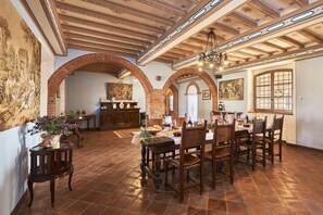 Une salle à manger spacieuse avec un plafond haut, des arches en briques et un lustre.