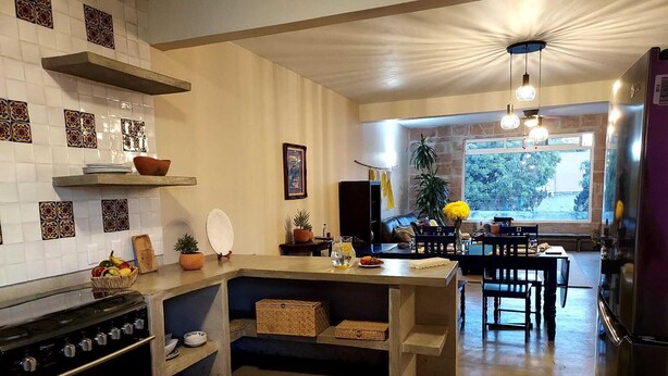 Une cuisine moderne dotée d’un four encastré, un coin repas avec une table et des chaises, et une vue sur l’extérieur grâce à une grande fenêtre.