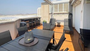 Eine Dachterrasse mit Tisch, Stühlen und Grill.
