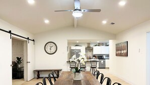 A dining area with a wooden table, black chairs, a clock, and a ceiling fan. - Big and Beautiful in Dallas (Dallas)