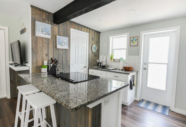 A kitchen with a granite countertop, white cabinetry, and a wooden accent wall.