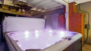 A hot tub with a ceiling fan above, a brick wall, and a door in the background. - Hot tub, Game Room, Outdoor Kitchen & much more! (Visalia)