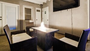 A room with a central table featuring a fire feature, surrounded by wicker chairs with cushions. - Hot tub, Game Room, Outdoor Kitchen & much more! (Visalia)