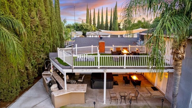 A covered patio with outdoor seating, a barbecue area, and a view of the surrounding landscape. - Hot tub, Game Room, Outdoor Kitchen & much more! (Visalia)
