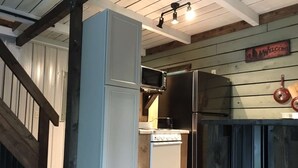 A compact kitchen with a white refrigerator, a microwave, and a stove.