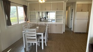 A spacious kitchen with white cabinets, a dining table with chairs, and a ceiling fan. - Ranch House (Woodlake)