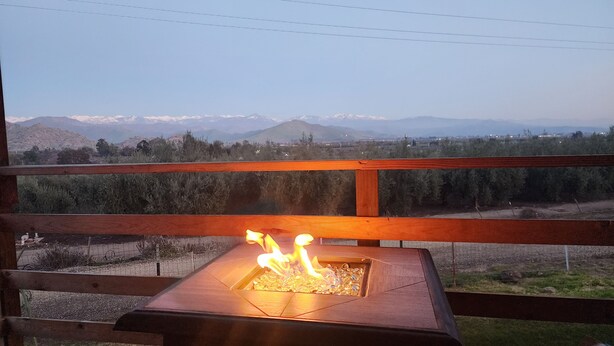 A wooden deck with a fire feature and a view of snow-capped mountains in the distance. - Ranch House (Woodlake)