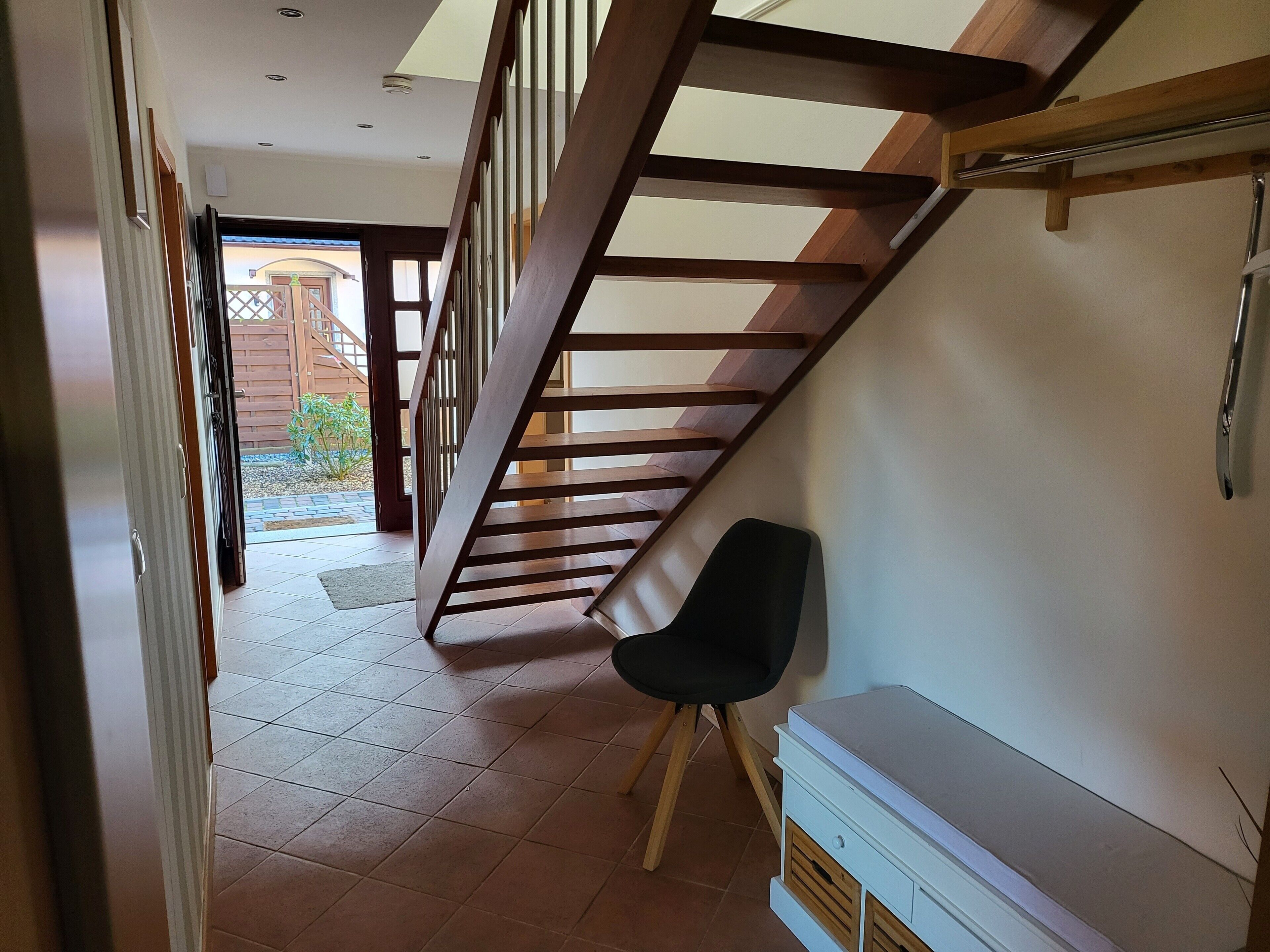 Eine Treppe mit Holzwertlauf, einem schwarzen Stuhl und einem weißen Schrank.