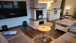 A living room with a flat-screen TV, leather sofas, a coffee table, and a fireplace. - Holiday Home 'Anker Perla' with Private Terrace and Wi-Fi (Grömitz)