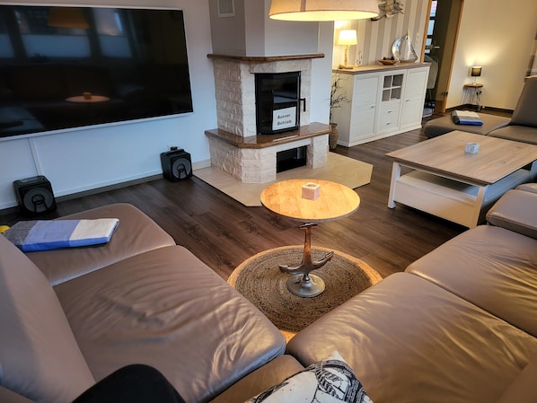 A living room with a flat-screen TV, leather sofas, a coffee table, and a fireplace.