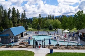 A pool area with a fenced pool, lounge chairs, and a small building with a blue roof. - Mountain Retreat, Spacious Cabin on 2.5 acres, firepit and trails (Garden Valley)
