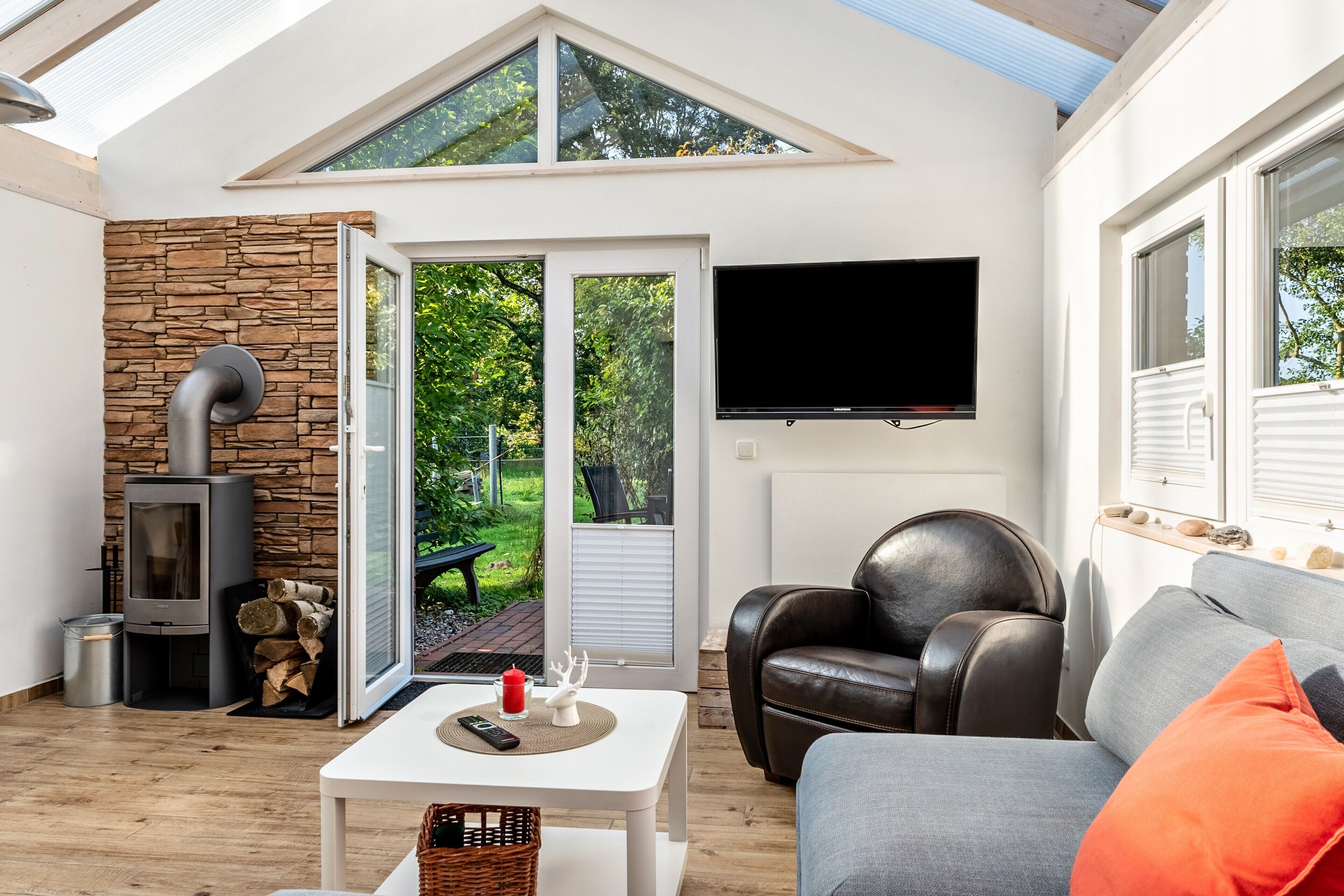 A cozy living room with a stone wall, a fireplace, a leather sofa, and a television.