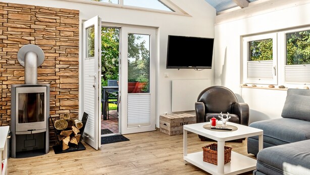 Una sala de estar moderna con una pared de piedra, chimenea, televisor y sofá.