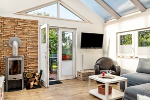 Una sala de estar moderna con una pared de piedra, chimenea, televisor y sofá.