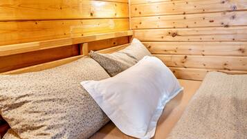 Una habitación de cabaña de madera con cama, almohadas y cabecera.