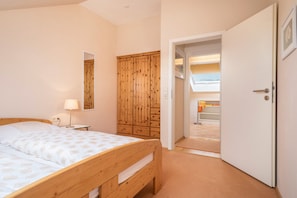 Una camera da letto con un letto di legno, un armadio, uno specchio e una porta che dà su un'altra stanza.
