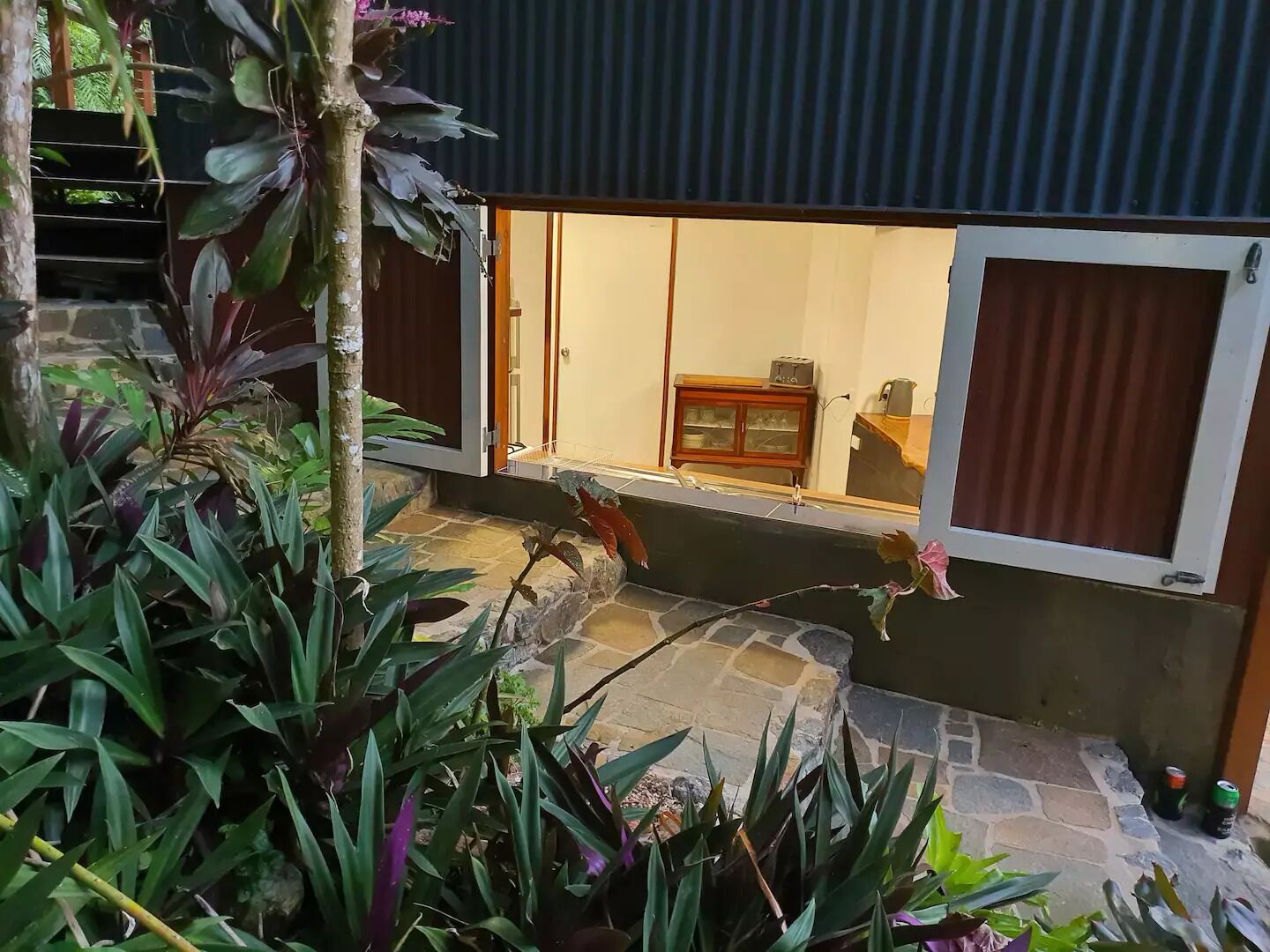 Quarto com soalho de pedra, um armário de madeira e janela com cortinas.