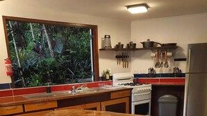 Une cuisine avec un îlot central en bois, une cuisinière et une fenêtre donnant sur un paysage verdoyant.