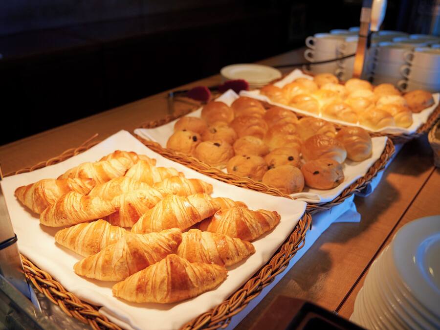 A buffet table with various baked goods, including croissants and other pastries, arranged in baskets.