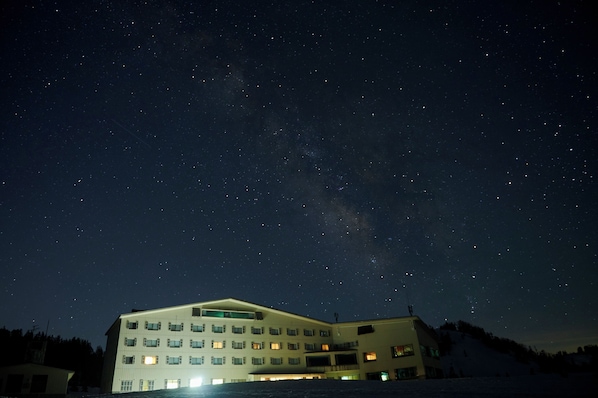 A building with multiple floors and windows, under a starry night sky.