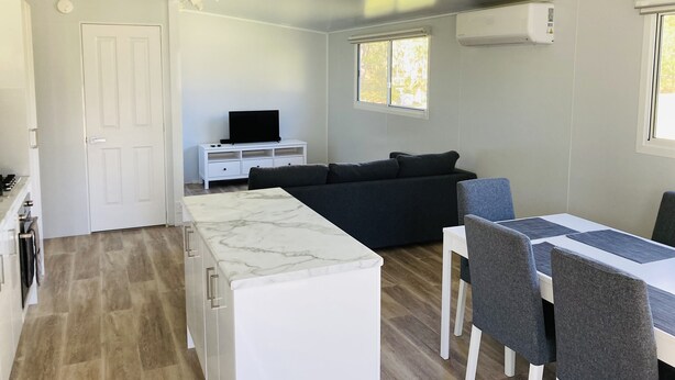 A modern, compact living space with a kitchen, dining area, and a sofa. - Modern Cottage amongst nature (Castlereagh)