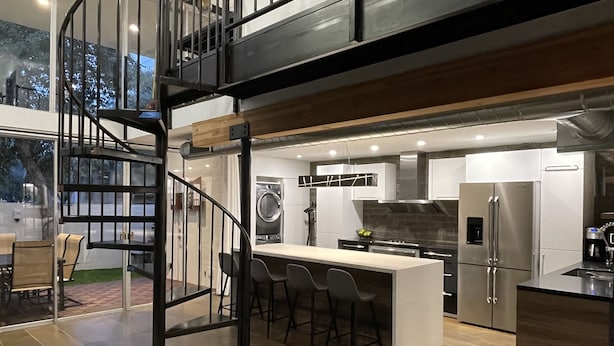 A modern kitchen with a central island, a dining area with bar stools, and a staircase leading to an upper level. - 3b/2b "Beadle Box" Architectural Loft w/ Doghouse + Golf (Mesa)