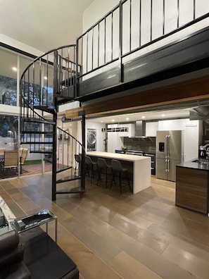 Enjoy a spacious open-plan living area with a sleek staircase, central island, and large windows offering views of the surrounding area.