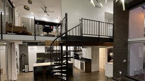 A modern interior with a central staircase, a kitchen, and a living area with a glass coffee table. - 3b/2b "Beadle Box" Architectural Loft w/ Doghouse + Golf (Mesa)
