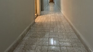 A narrow hallway with tiled flooring and a light fixture on the ceiling. - Casa de Praia 80 Metros do mar (Itanhaém)