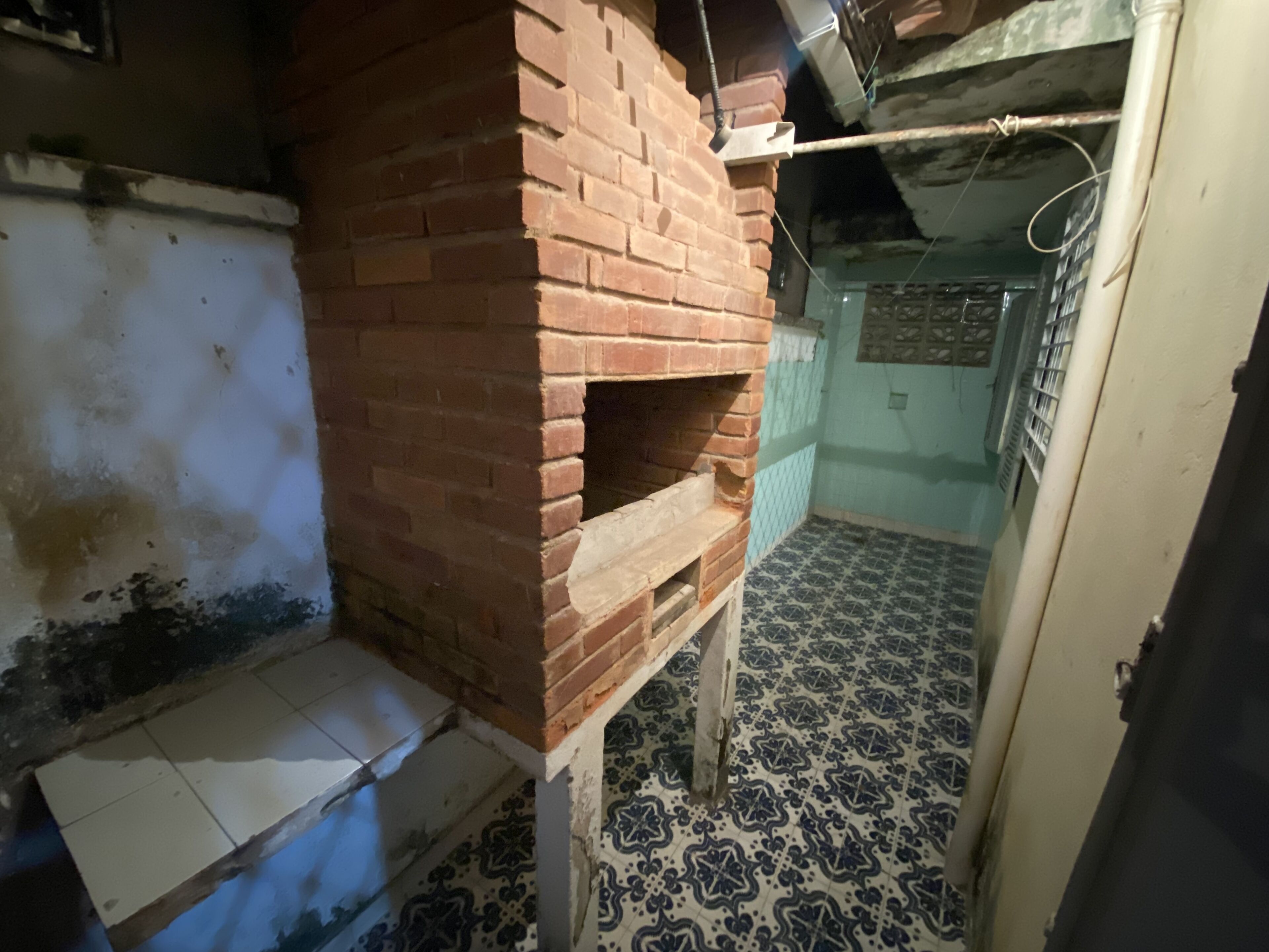 A room with a brick fireplace, tiled floor, and a partially visible door.