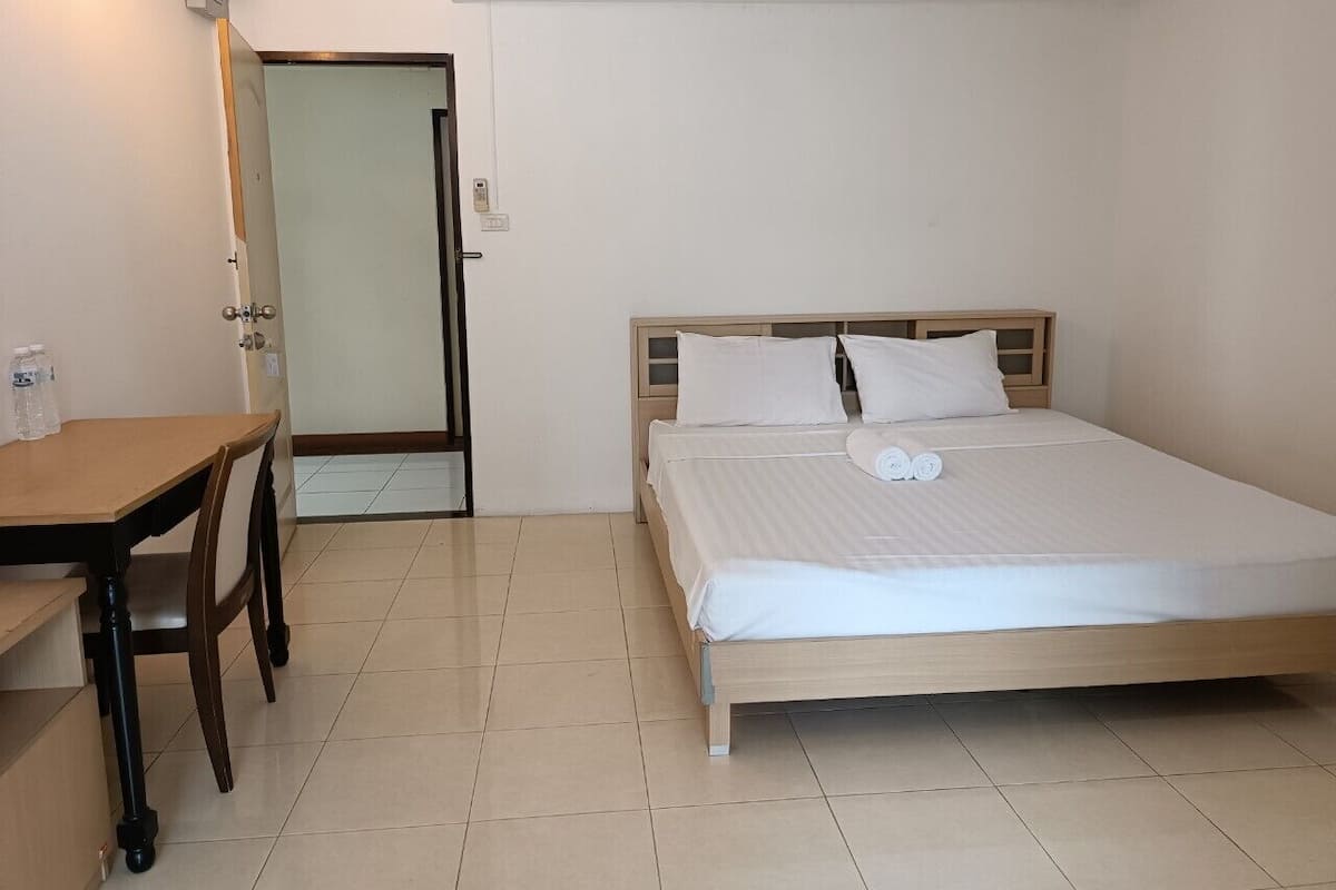 A hotel room with a bed, a wooden desk, and a chair.