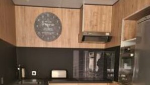 Una cocina moderna con armarios de madera, un refrigerador de acero inoxidable y una encimera negra.