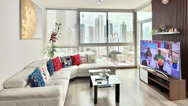 Una sala de estar moderna con un sofá grande, una mesa de centro y un televisor.