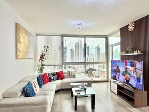 Ein modernes Wohnzimmer mit einer großen Couch, einem Couchtisch und einem Fernseher.