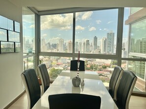 Panoramic city views from a spacious office with a large window, conference table, and comfortable seating for four.