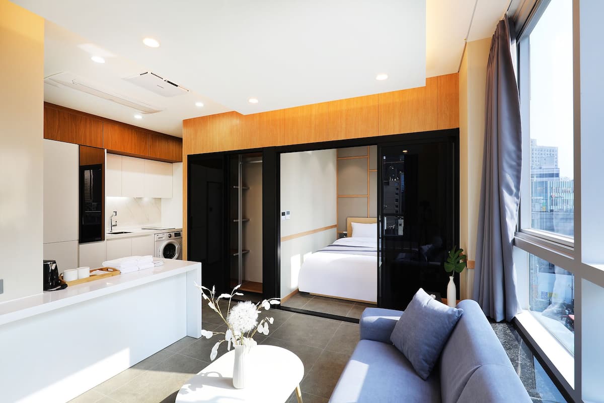 Een moderne hotelkamer met kitchenette, een groot bed, een bank en uitzicht op de stad.