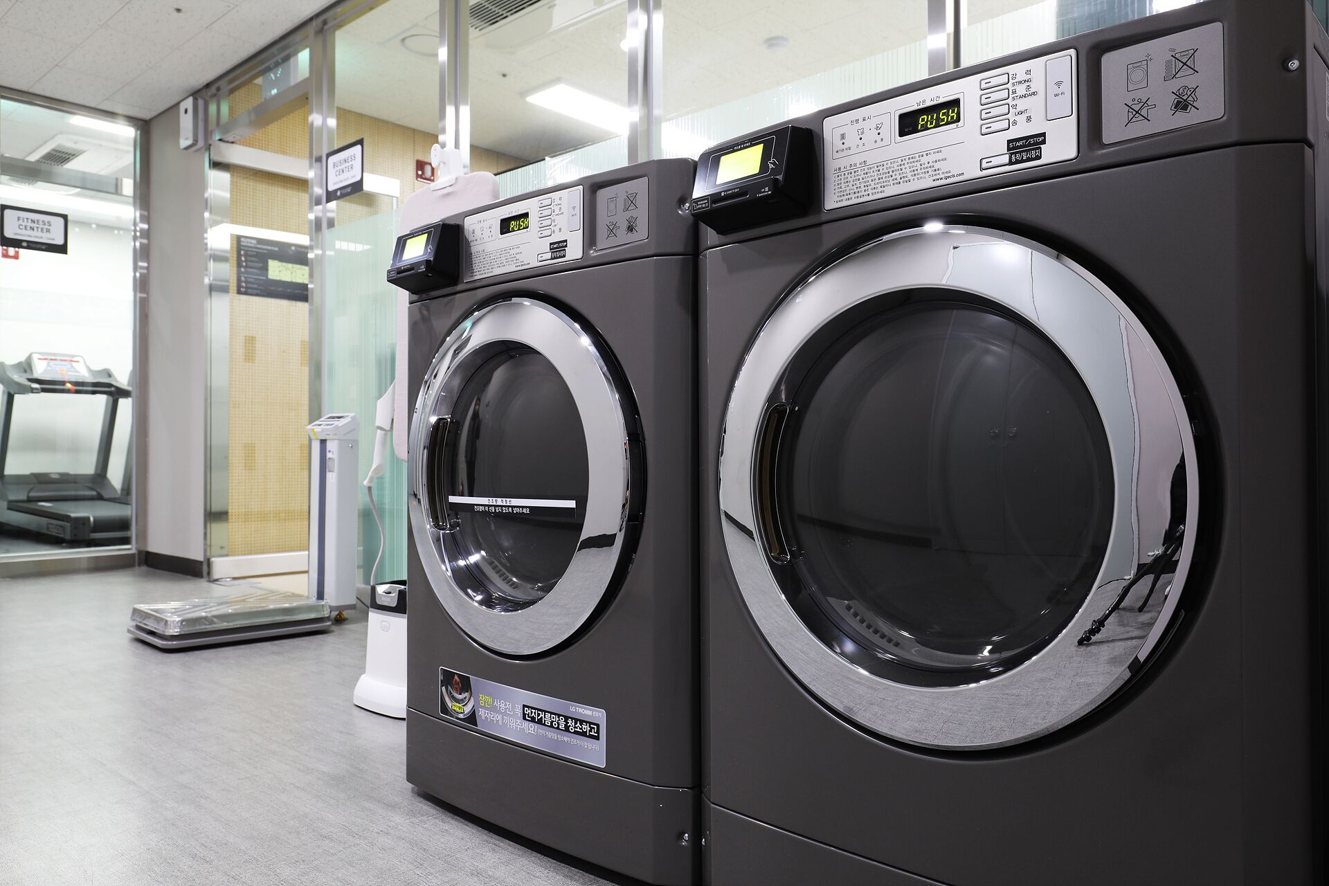 A row of front-loading washing machines in a commercial setting.