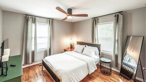 A bedroom with a bed, a ceiling fan, a bedside table with a lamp, a mirror, and a green desk with a chair. - Spring is Coming!  29 Miles to Nash, 1 Mile Downtown Gallatin (Gallatin)