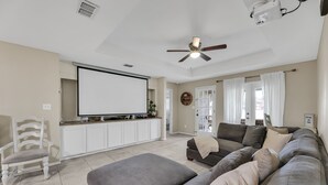 A living room with a large flat-screen TV, a ceiling fan, a sofa, and a coffee table. - The Cozy Houz at Cimarron! With Golf Course View (Mission)