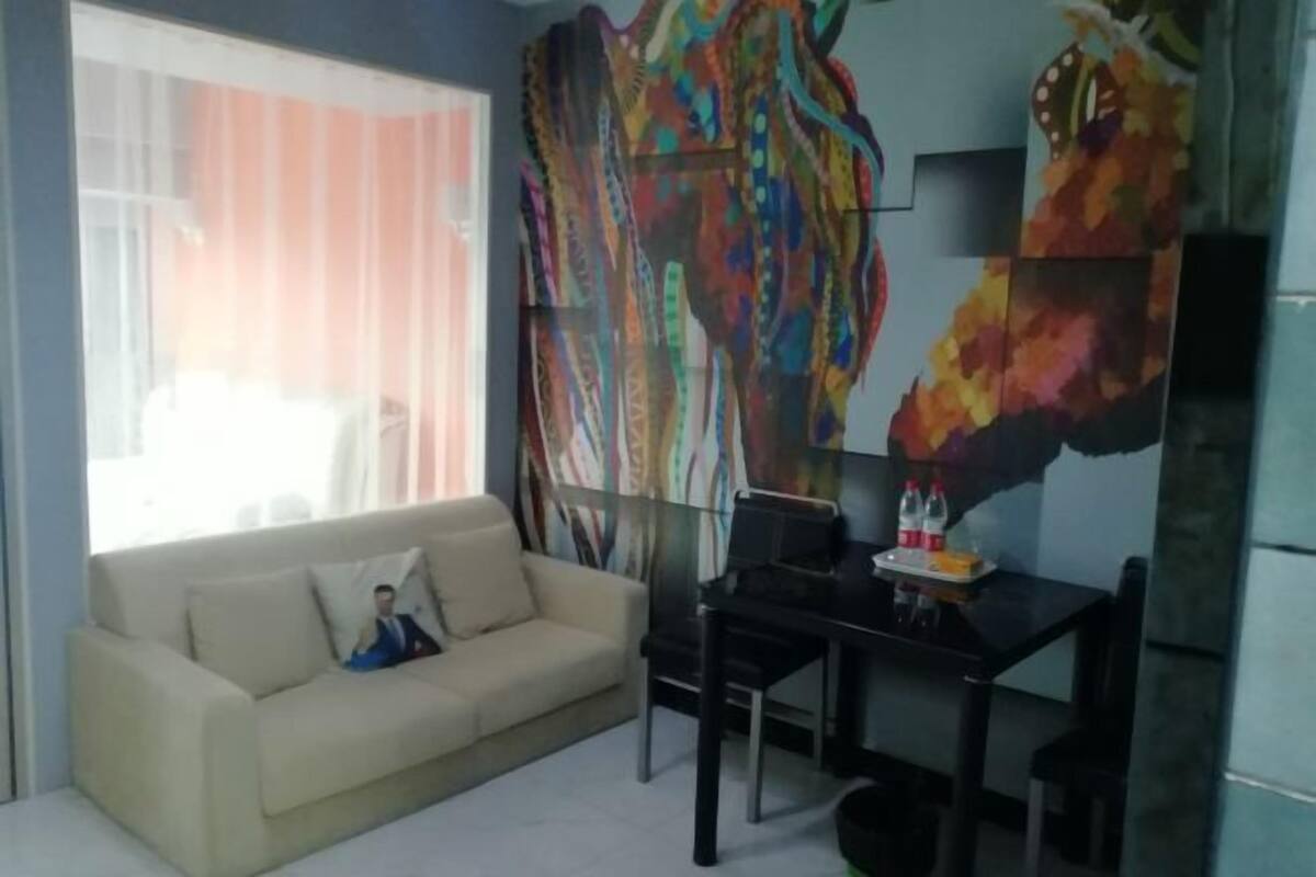 A living room with a sofa, a coffee table, and a desk with chairs.