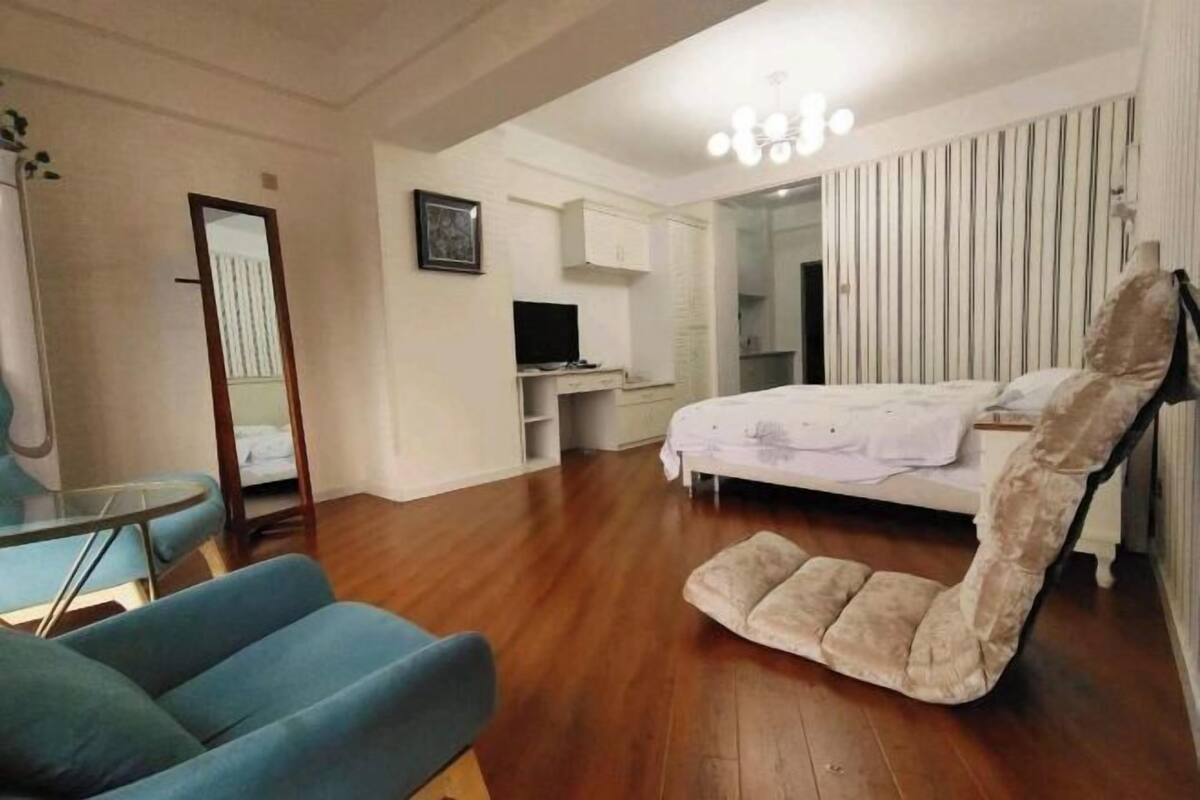 A bedroom with a bed, a chair, a desk, and a mirror.