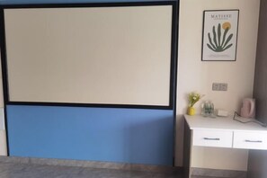 A room with a large whiteboard, a desk with drawers, a framed artwork of a plant, and a vase with flowers. - Chuzhou Aidi Daily and Short-Term Rental Luxury Apartment (Chuzhou)