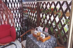 A wicker chair, a small round table with a floral tablecloth, and a decorative item on the table.