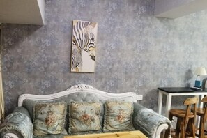 A room with a vintage sofa, a zebra artwork, a small table, and wooden chairs. - Chuzhou Aidi Daily and Short-Term Rental Luxury Apartment (Chuzhou)